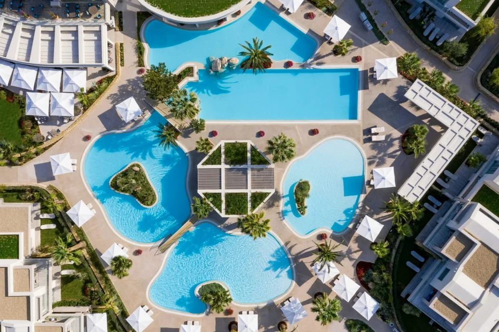 Aerial view of the lagoon-style pools and palm trees at Porto Sani