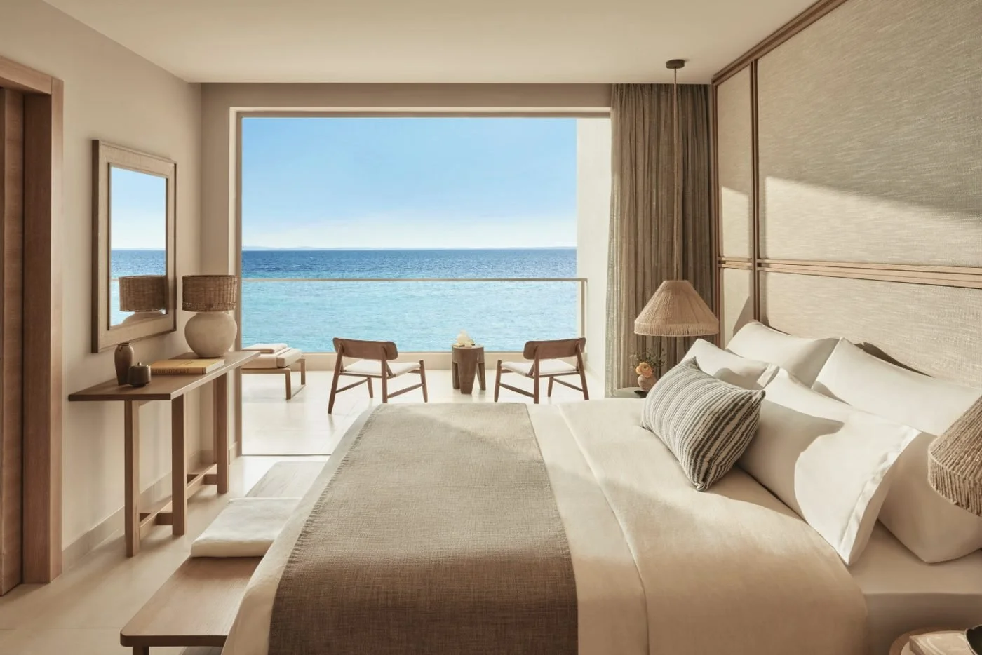 The bedroom of a beachfront Deluxe Two Bedroom Bungalow Suite looking straight out across its balcony to the sea