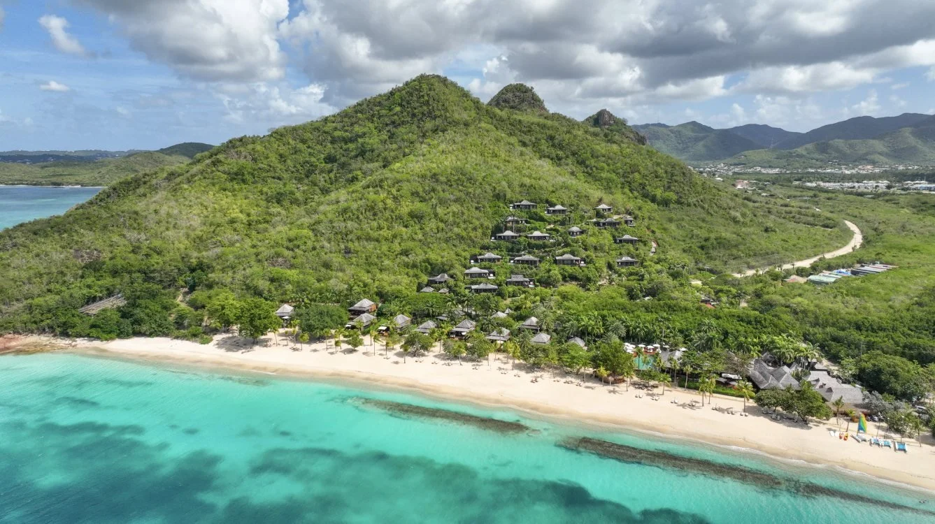 Hermitage Bay's villas on the hillside above a white sand beach and turquoise sea