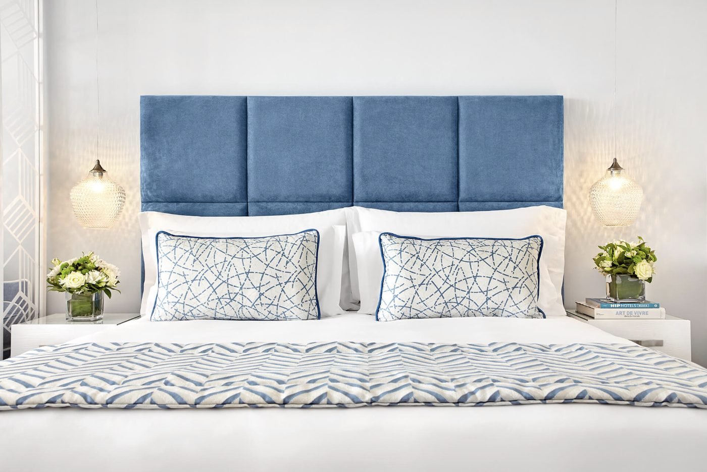 A Double Room at Ikos Oceania with a blue upholstered headboard and crisp white bedding