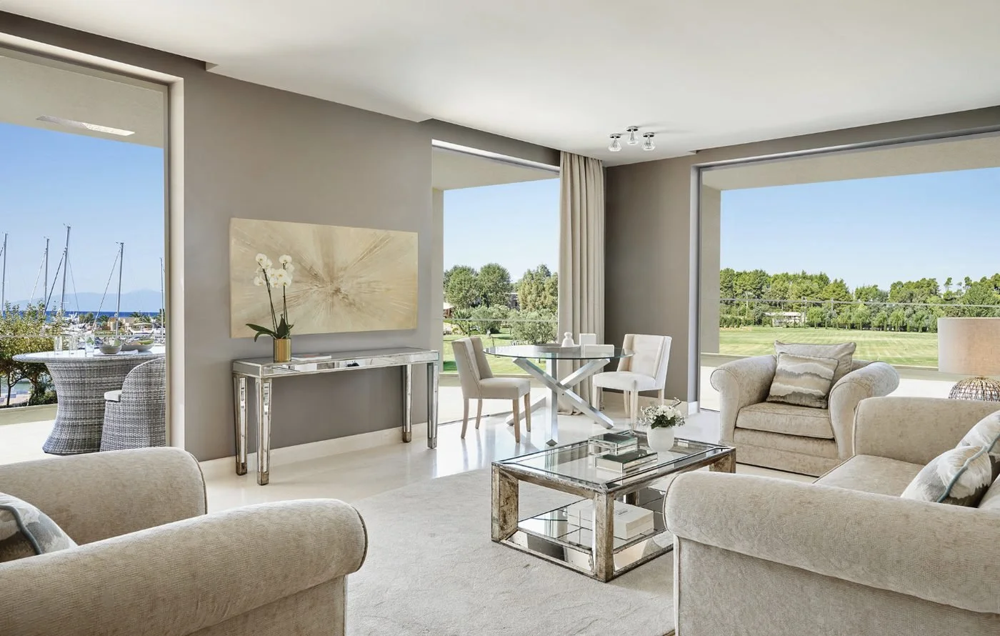 The living and dining area of a Three Bedroom Family Suite, with balconies looking towards the marina and gardens