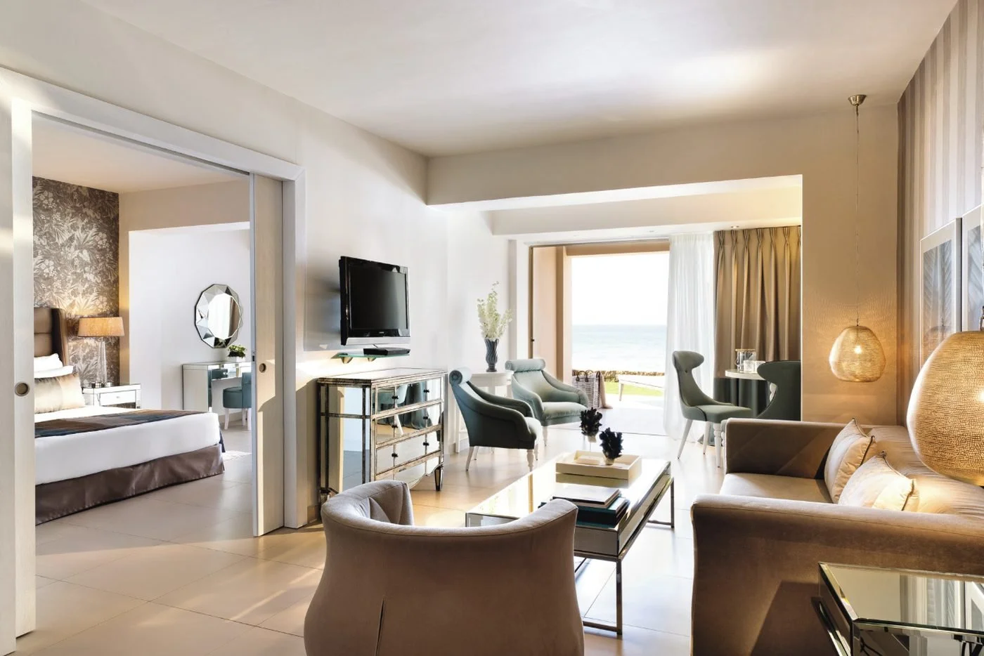 The living room of a One Bedroom Family Suite Beach Front opening onto its garden terrace and the sea