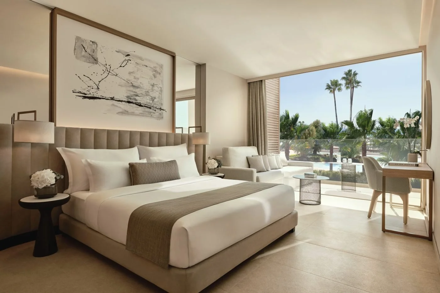 A Family Room at Ikos Andalusia with a double bed and a balcony overlooking palm trees and the pools