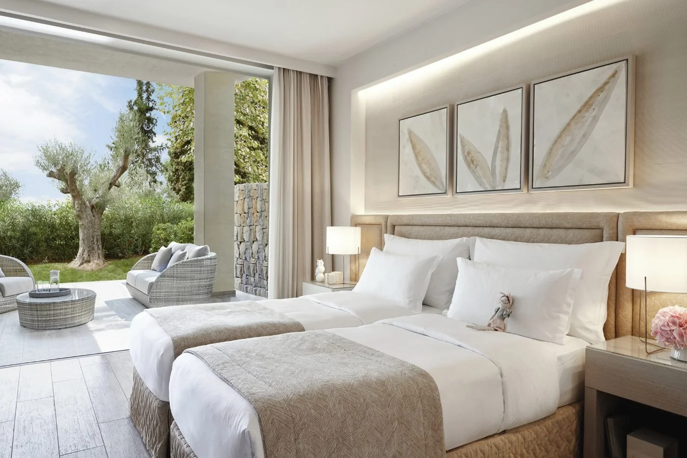 A twin bedroom in a Two Bedroom Family Suite opening onto a garden terrace with an old olive tree