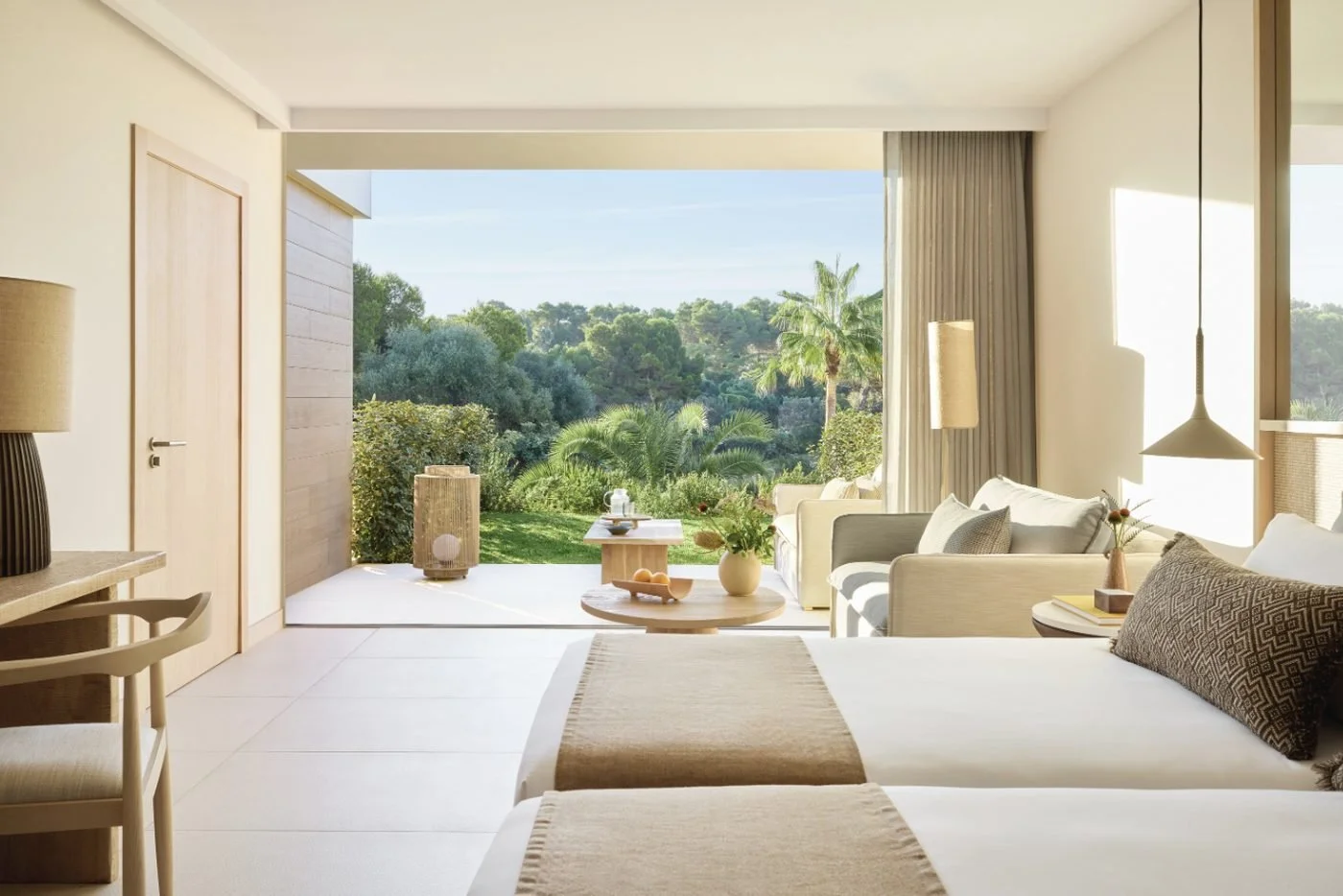A Family Room Private Garden with two beds and a sitting area opening onto a garden with palms