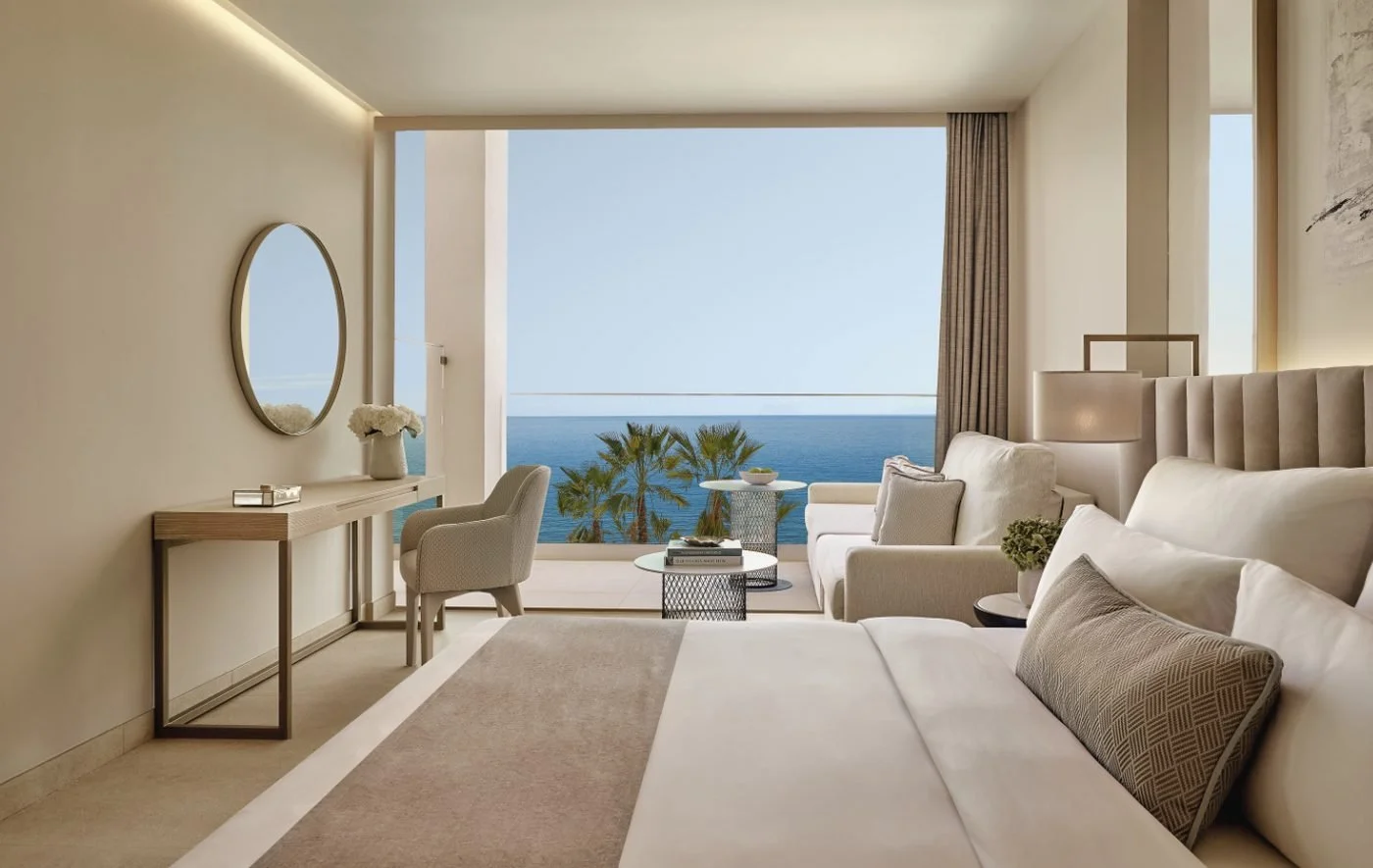 A Superior Double Room at Ikos Andalusia with full-length windows onto a balcony, palm trees and the sea