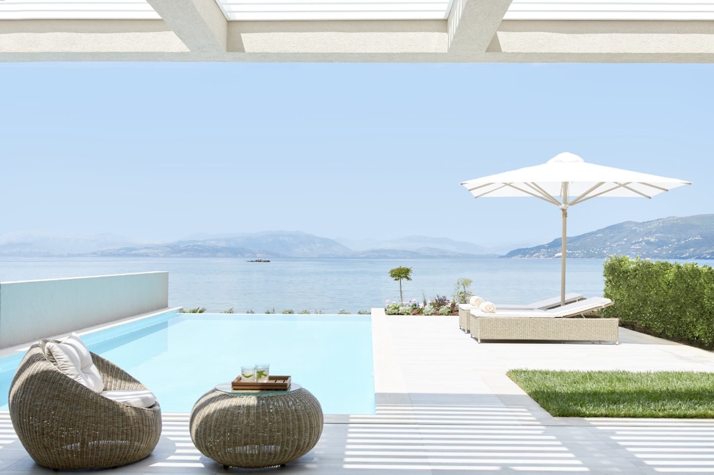 A private infinity pool and wicker loungers looking out over the sea from a Deluxe One Bedroom Suite Private Pool Beachfront