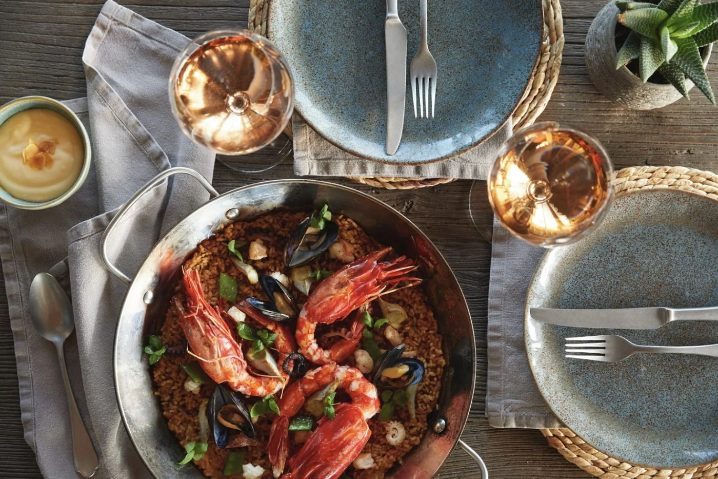 A pan of seafood rice with red prawns and mussels, with glasses of rosé, at El Puerto
