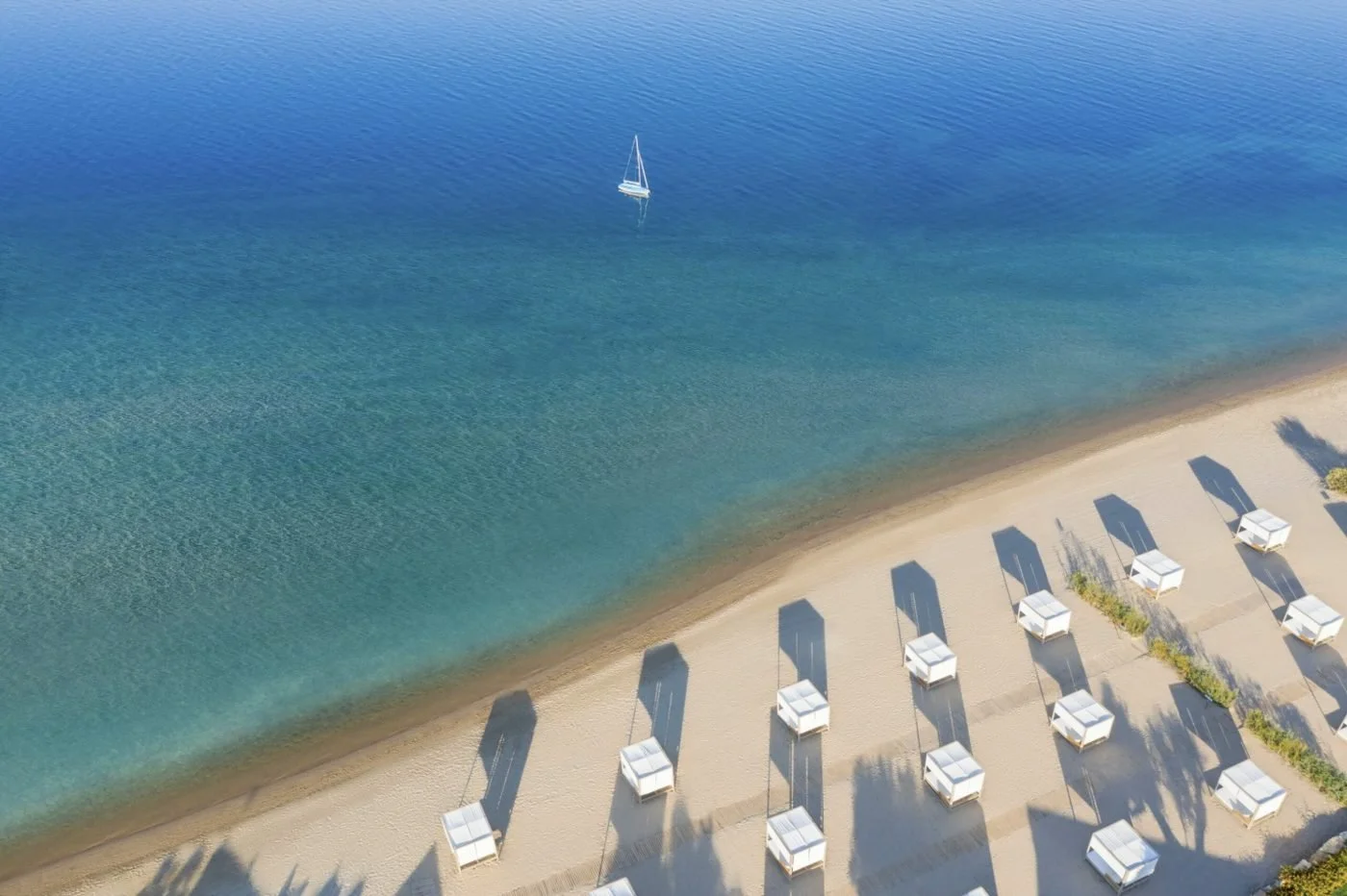 Rows of white cabanas on the golden beach at Ikos Olivia, with a yacht on the clear blue sea