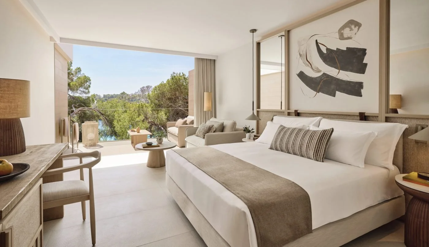 A Superior Double Room opening onto a balcony among the pines, with a glimpse of the sea