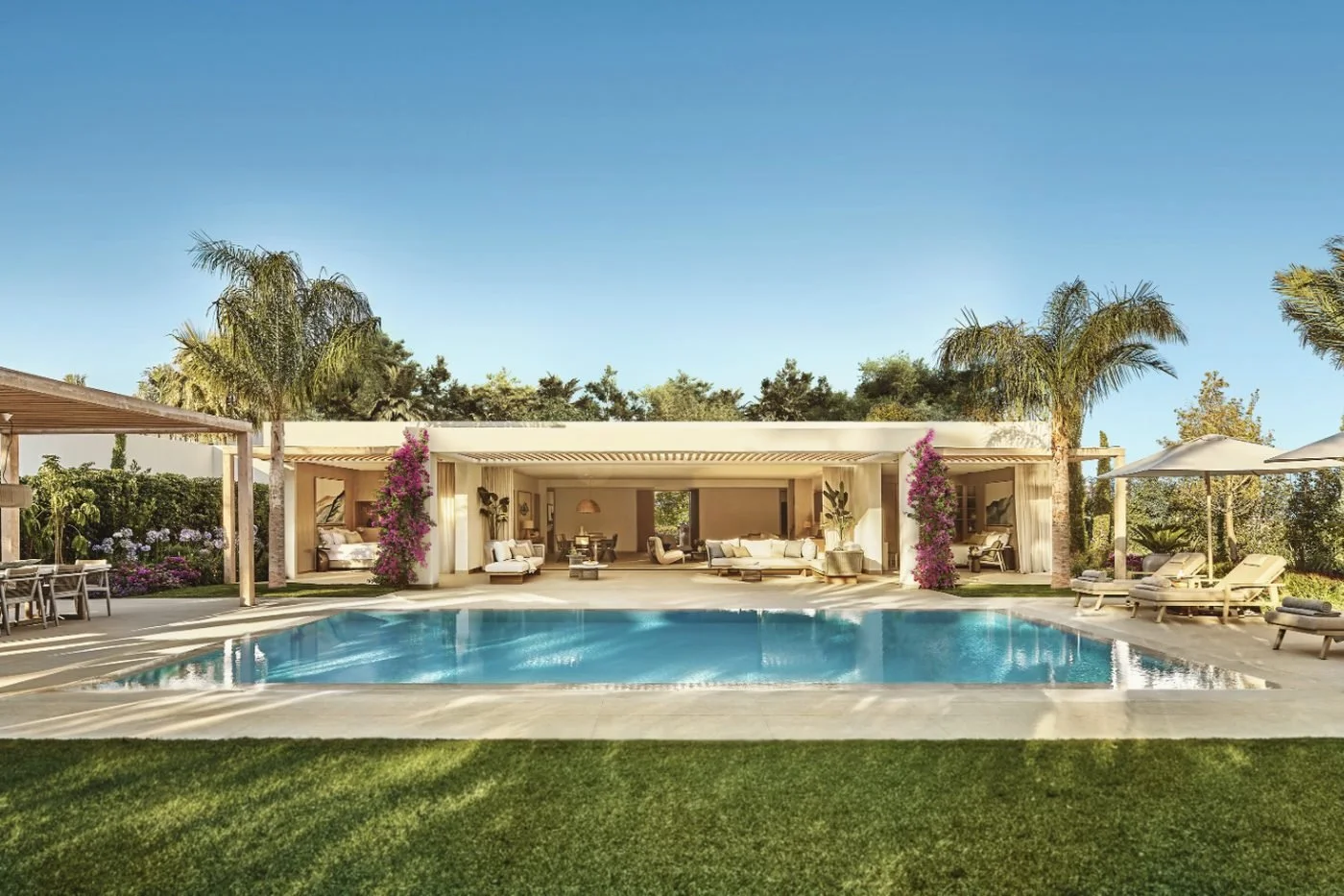 A Deluxe Four Bedroom Villa at Ikos Andalusia behind its private pool, lawn and palm trees