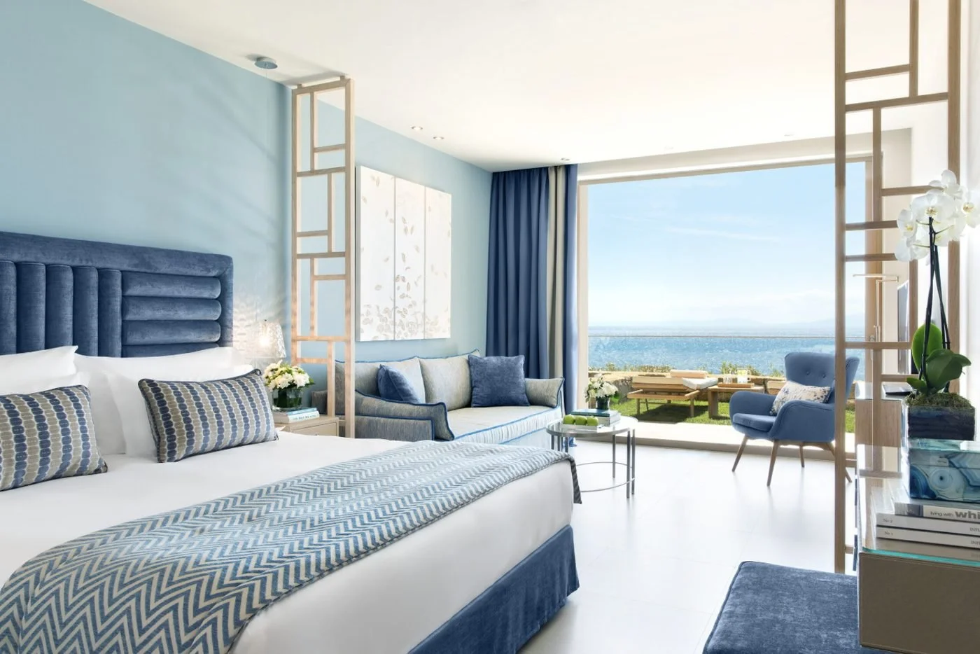 A Junior Suite Private Garden at Ikos Oceania with a king bed and doors open to a lawn and the sea