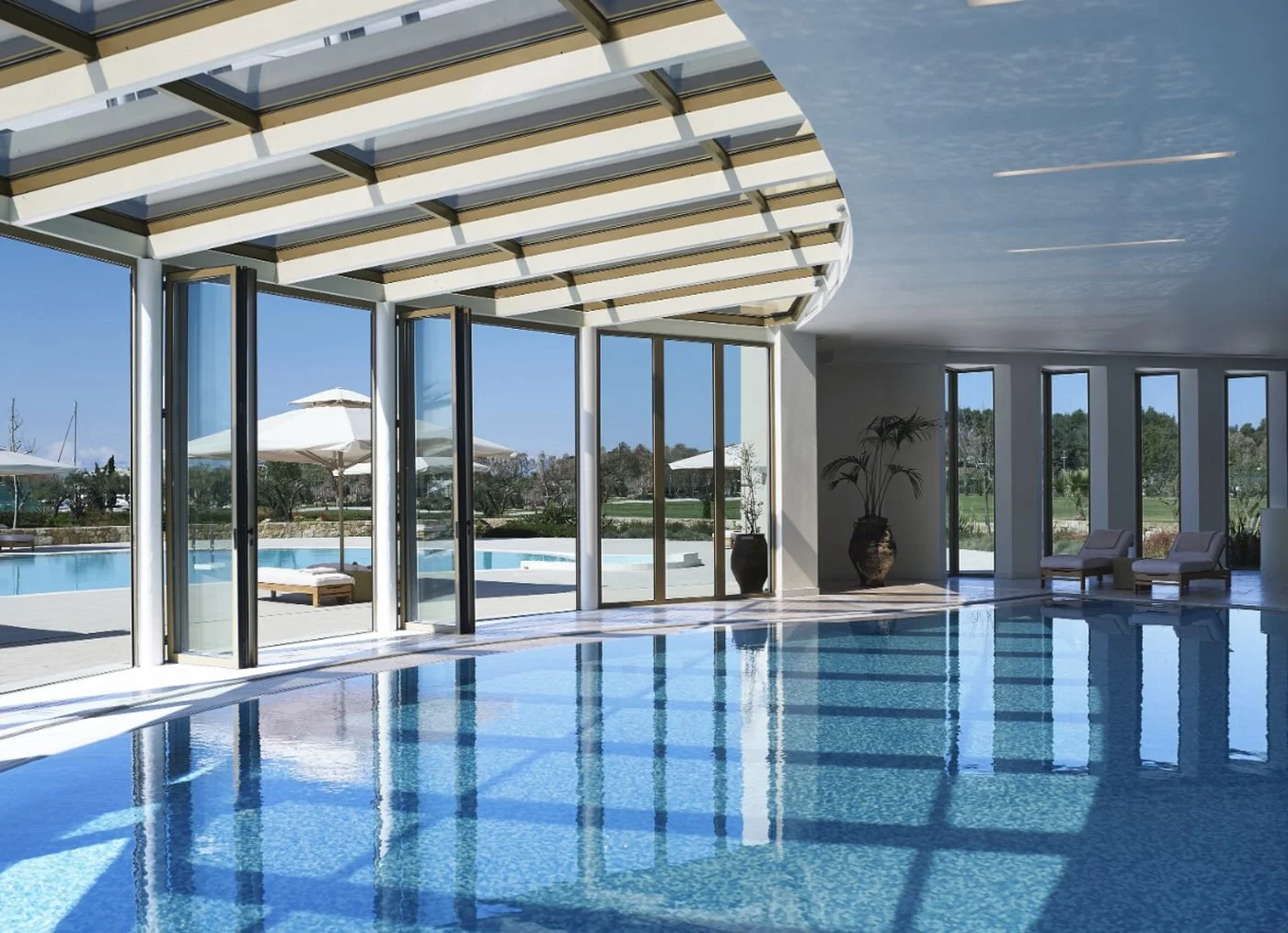 The heated indoor pool at the Spa Suite, beneath a glass roof with folding doors open to the gardens