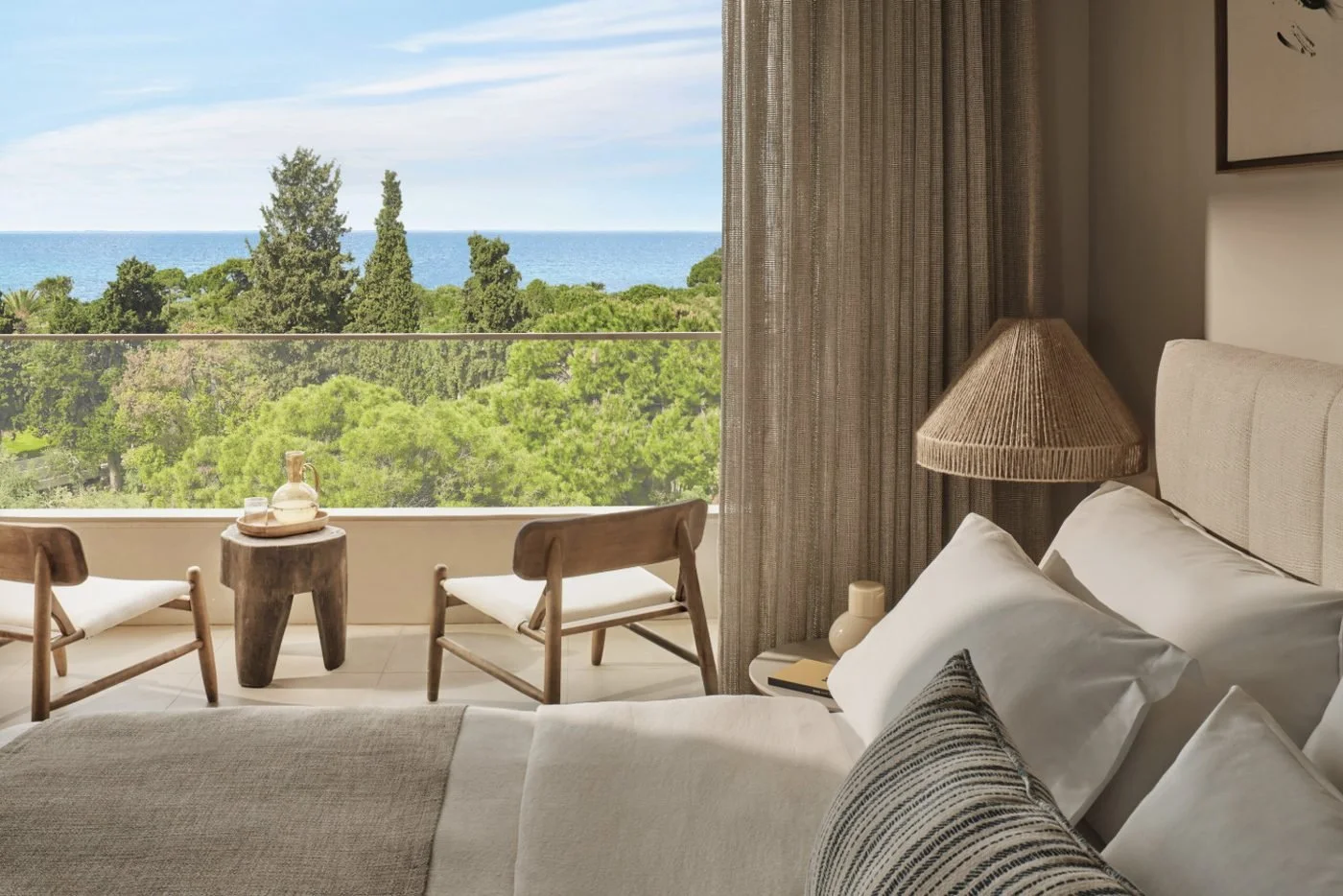 The view from the bed of a Panorama Junior Suite at Ikos Olivia, across its balcony and the pine trees to the sea