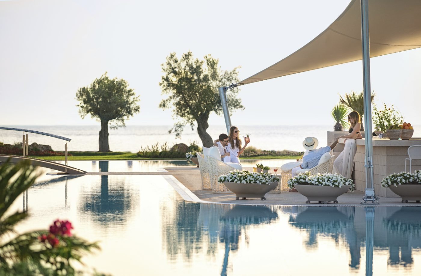 Friends with drinks at the poolside bar at Sani Dunes, beside the still lagoon pool and the sea