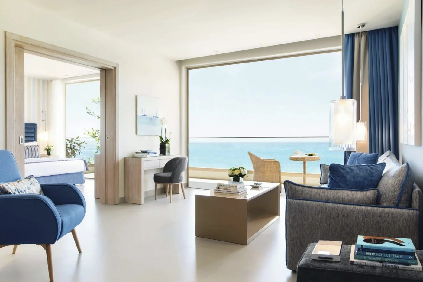 The living room of a Deluxe Two Bedroom Family Suite at Ikos Oceania, opening onto a balcony with a sea view