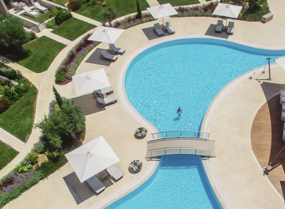 A swimmer in the lagoon pool at Sani Dunes, crossed by a small bridge