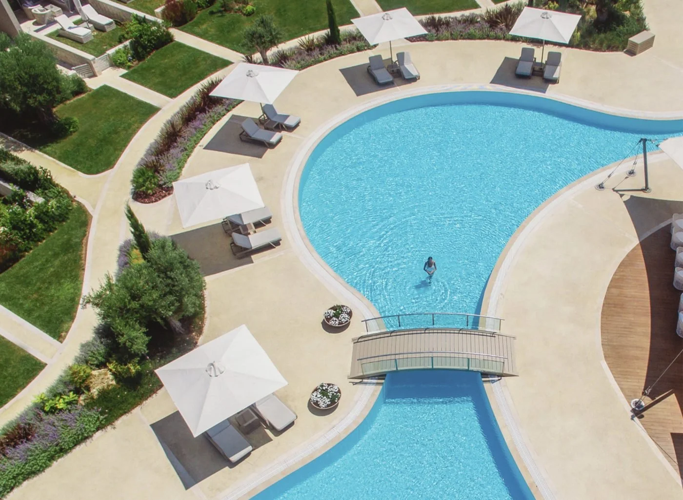 A swimmer in the lagoon pool at Sani Dunes, crossed by a small bridge