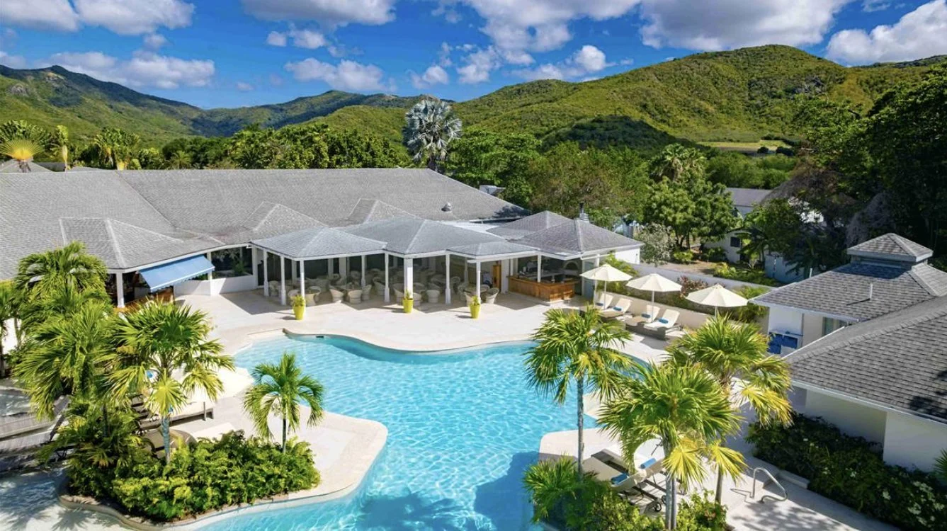 Carlisle Bay's pool and pavilion with rainforest hills behind