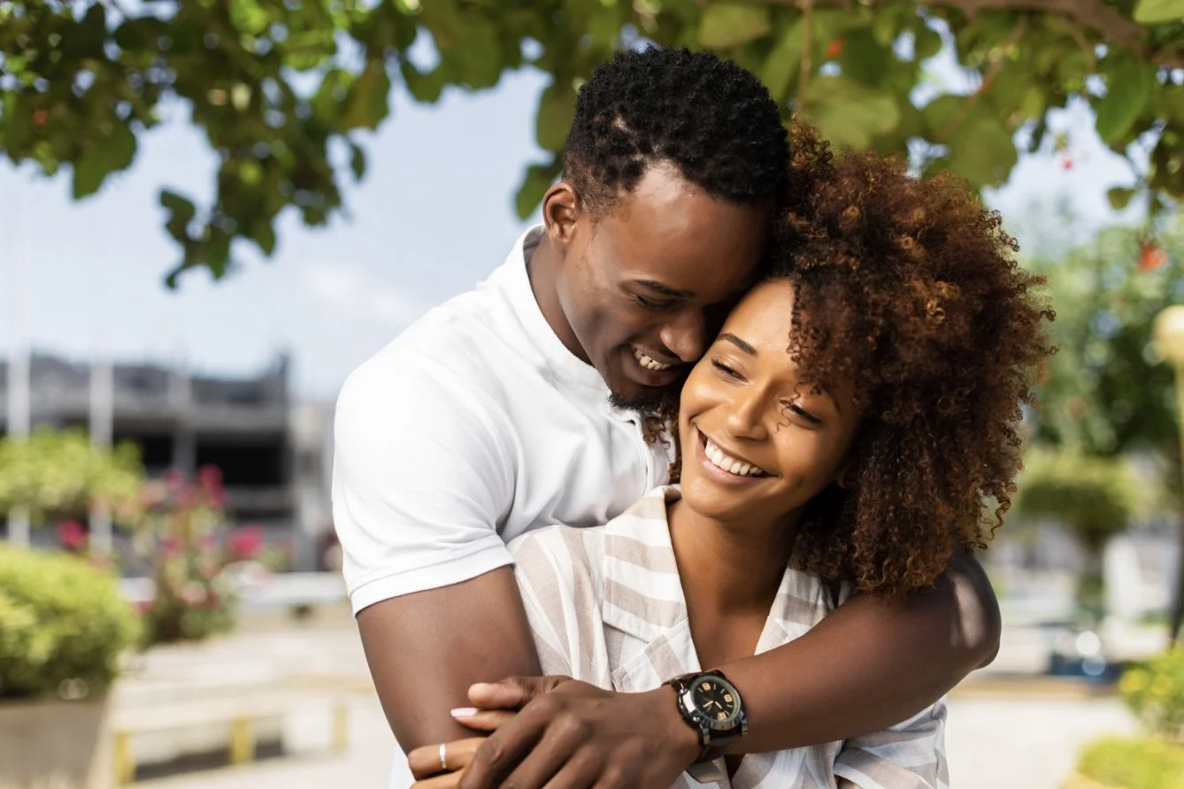 A smiling couple embracing in a sunny garden