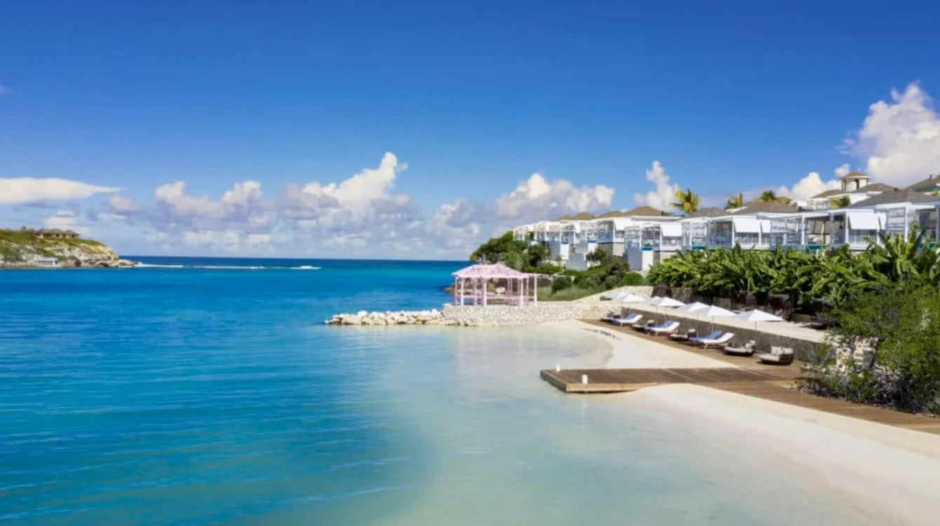 The beach and jetty with villas on the hillside