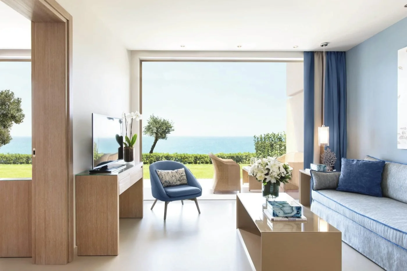 The lounge of a One Bedroom Family Suite Private Garden opening onto its lawn above the sea