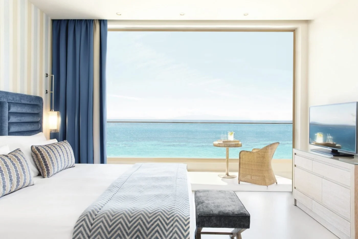 A Superior Double Room at Ikos Oceania with floor-to-ceiling windows onto a balcony and the sea