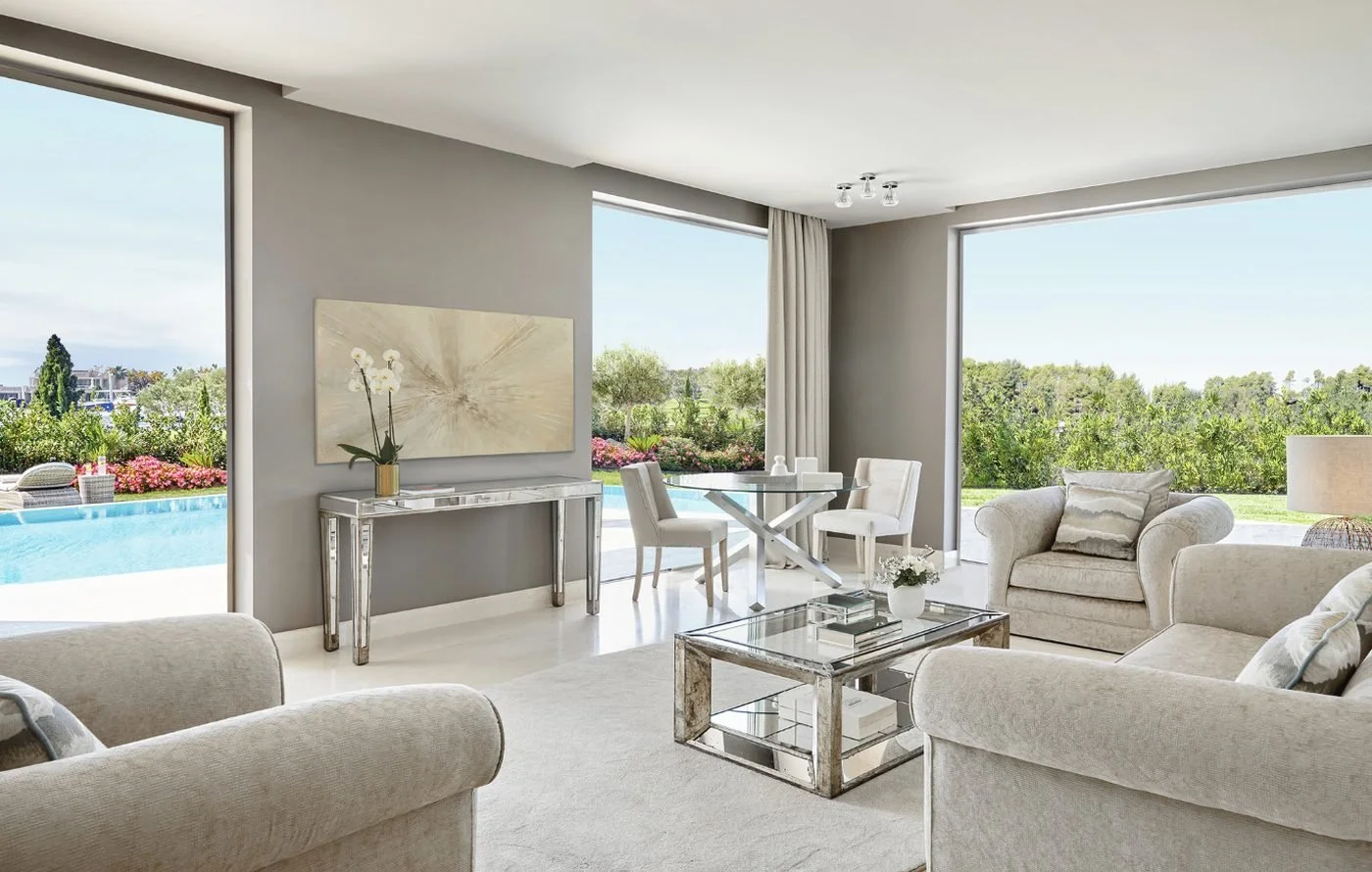 The living room of a Three Bedroom Family Suite opening onto its private pool and a flowering garden