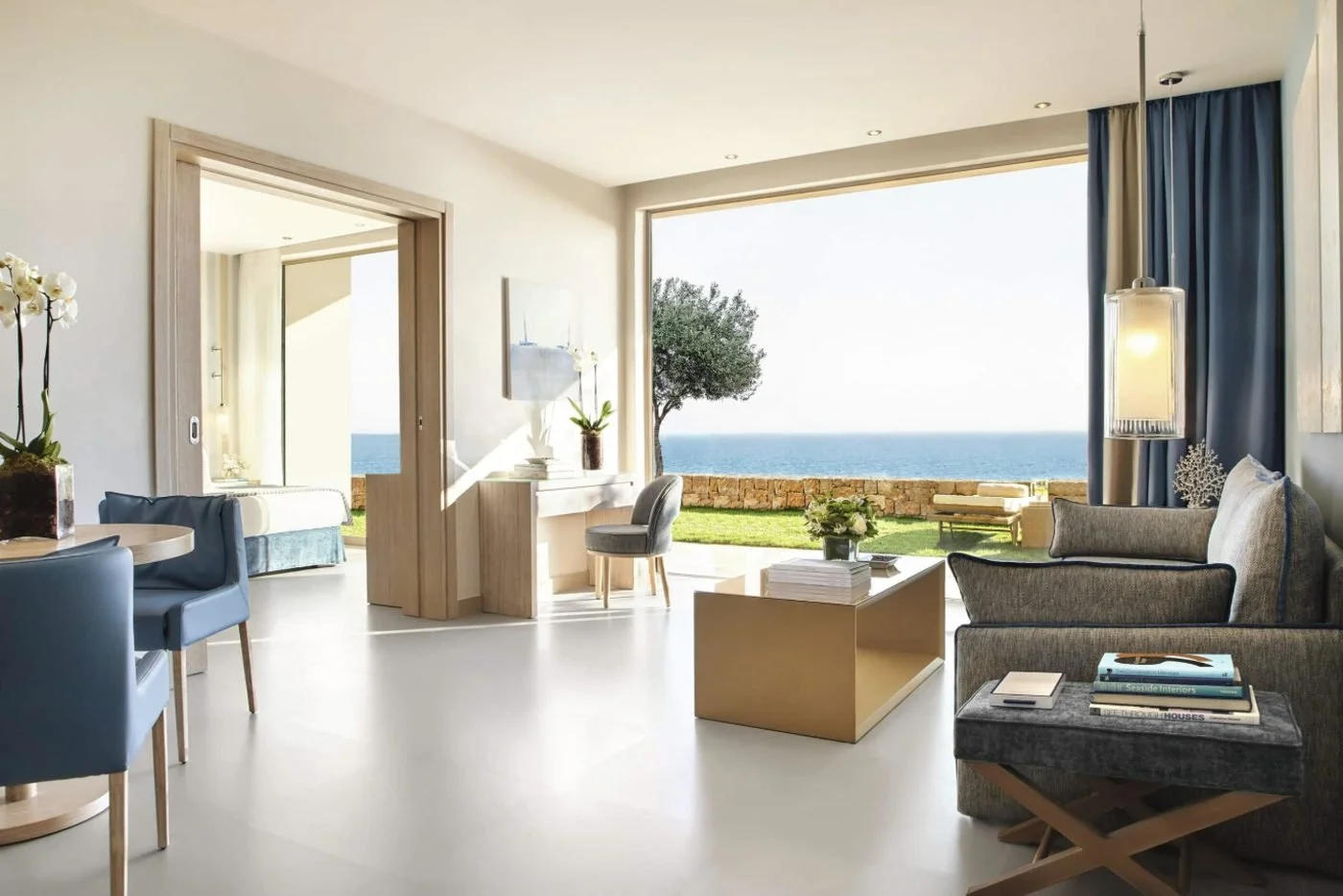 The living room of a Deluxe Two Bedroom Family Suite Private Garden opening onto a lawn above the sea