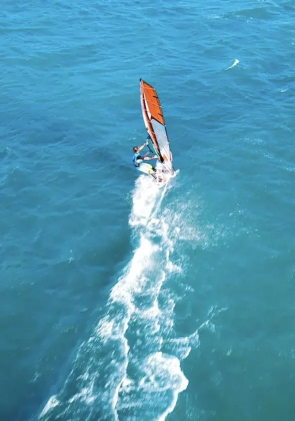 A windsurfer carving across bright blue water