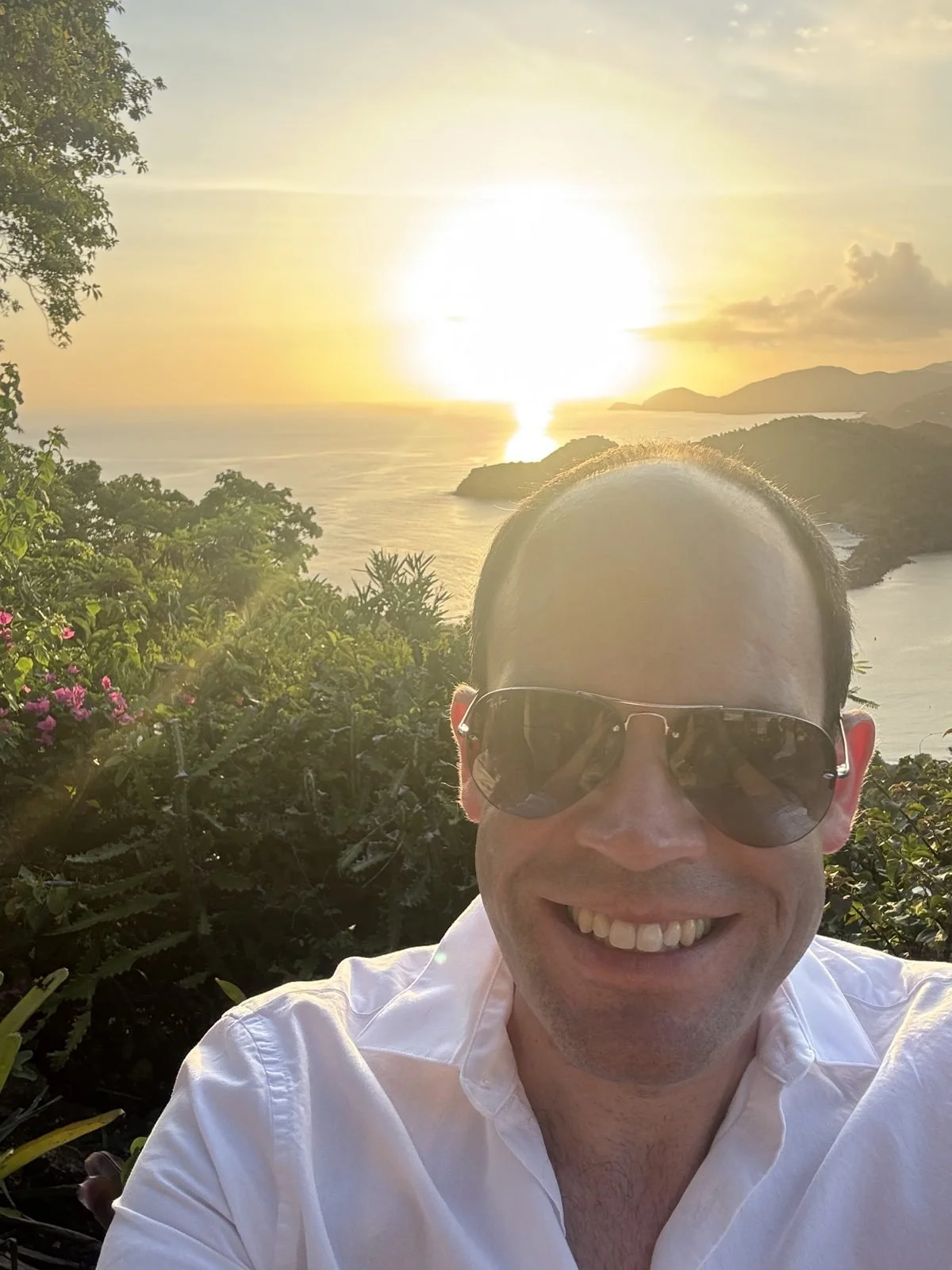 Ben smiling in the evening sun with the sea behind