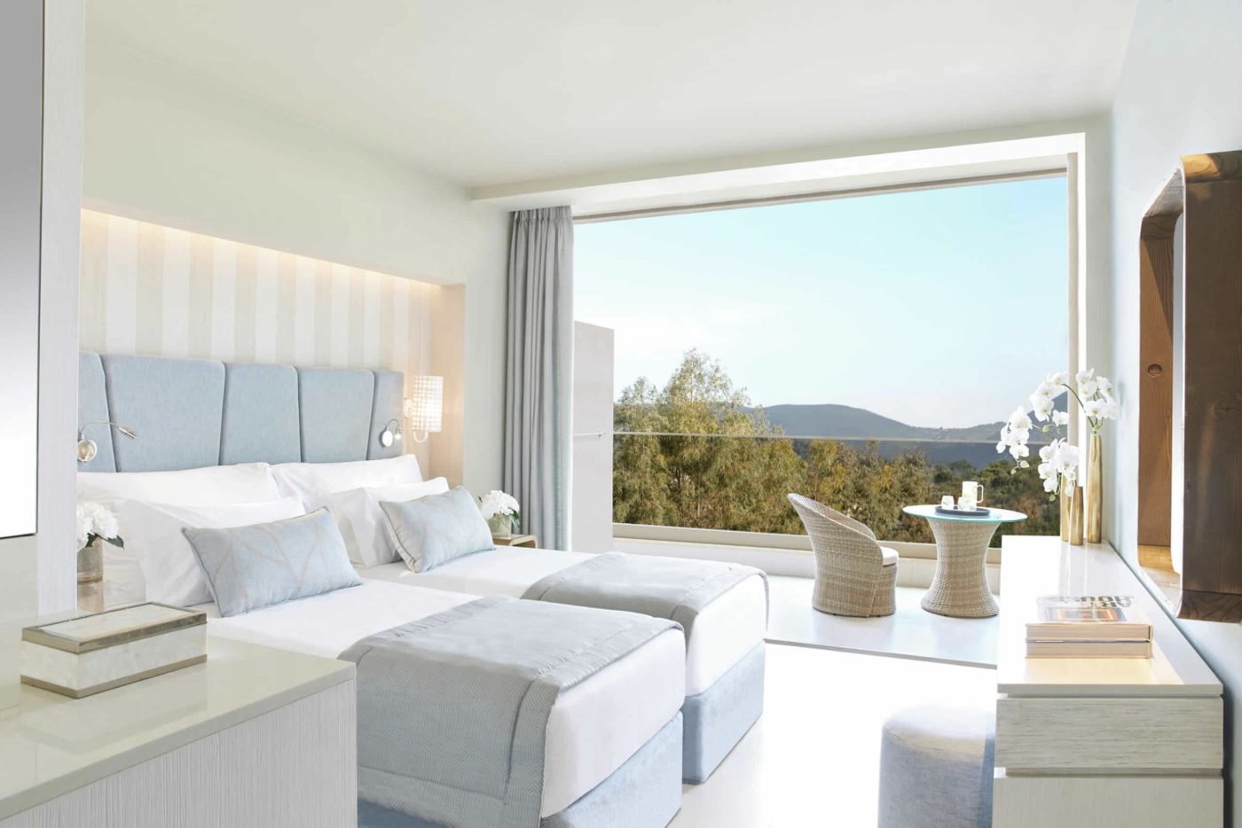 A Family Room with twin beds and a large window looking out to wooded hills and the bay