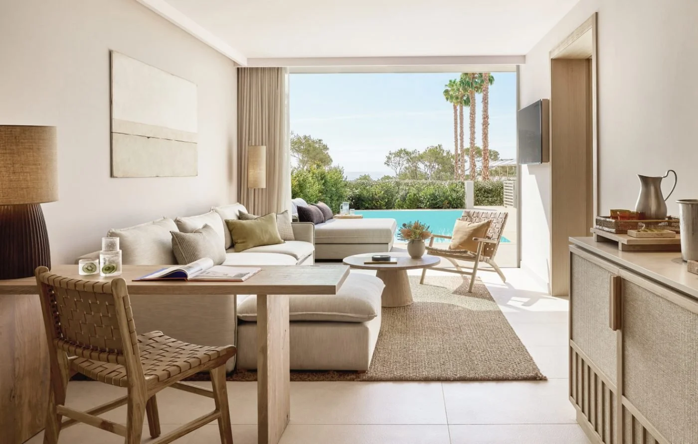 The lounge of a Deluxe One Bedroom Suite opening onto its private pool and palm trees