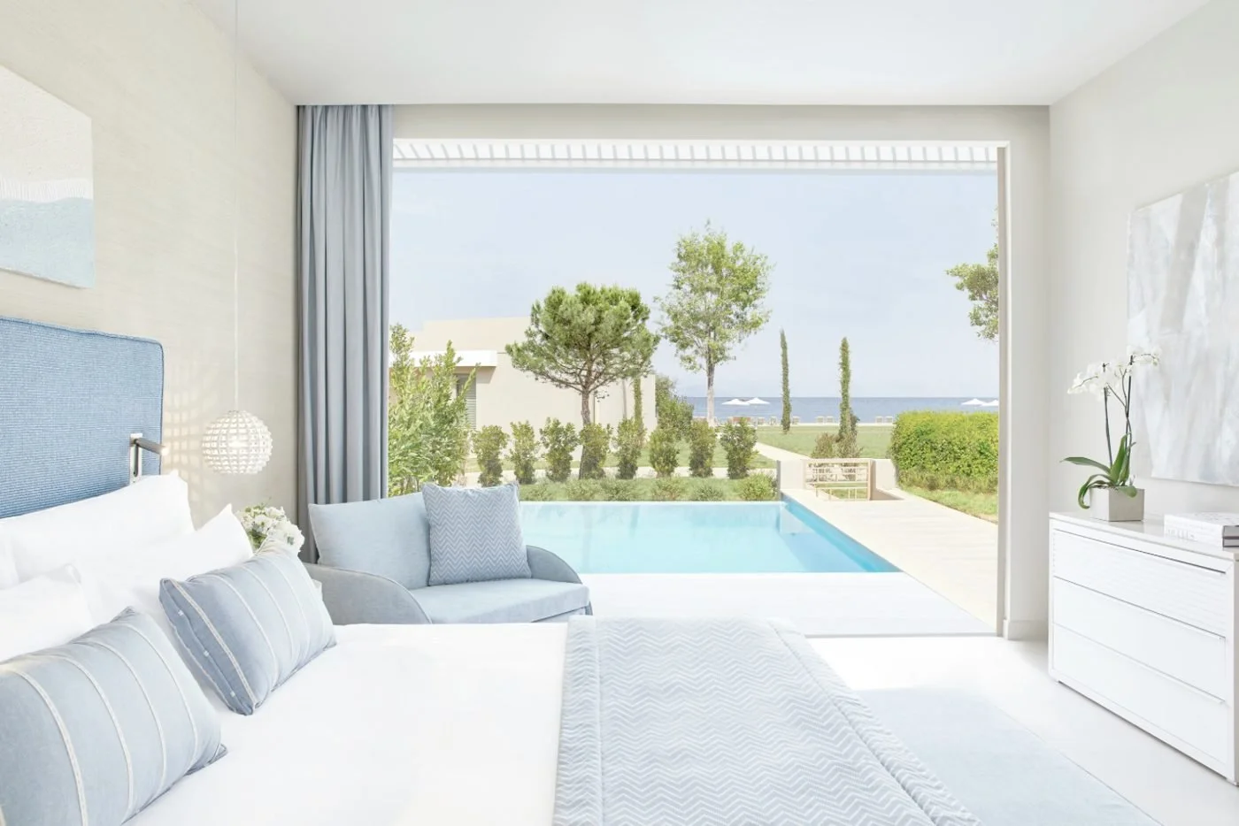 A Deluxe Junior Suite Bungalow Private Pool, its bed facing glass doors that open onto a private pool and garden