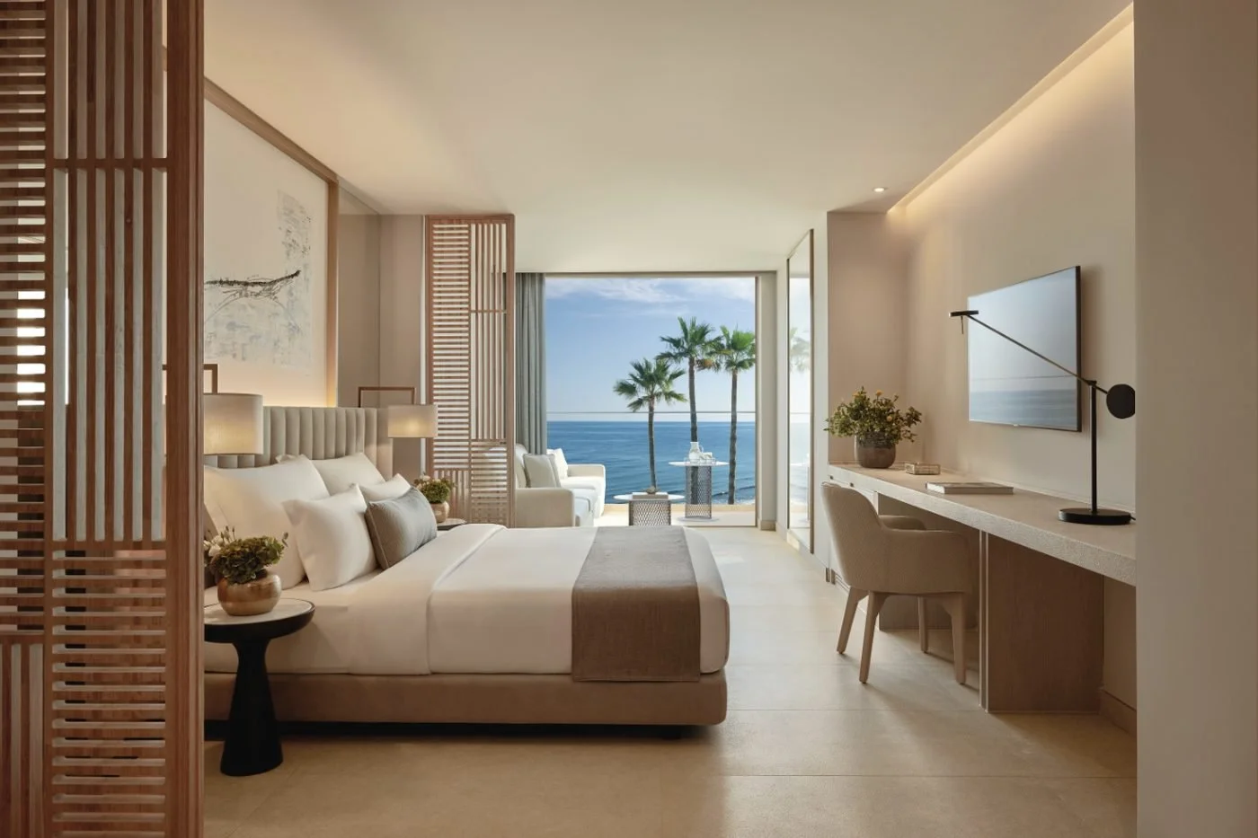 A Deluxe Junior Suite at Ikos Andalusia with a double bed and a balcony framing palm trees and the sea