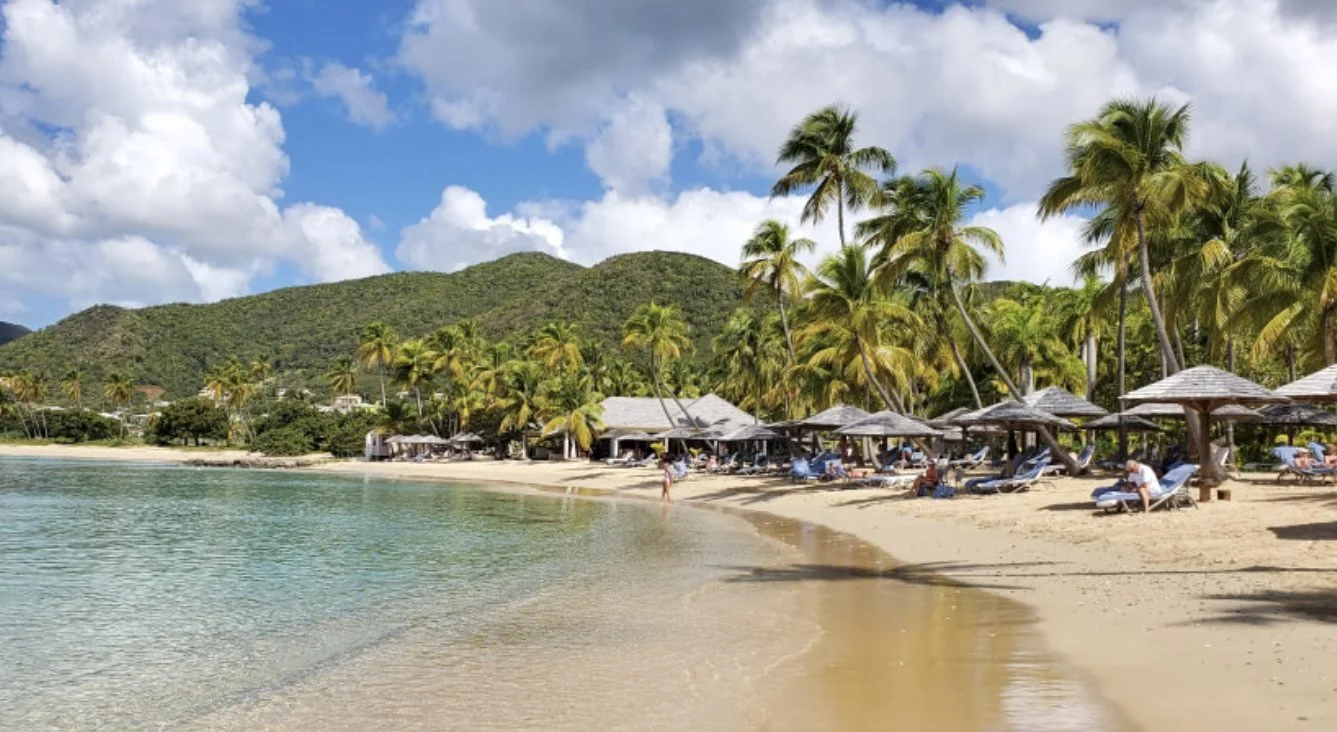 Curtain Bluff's palm-fringed beach with green hills behind