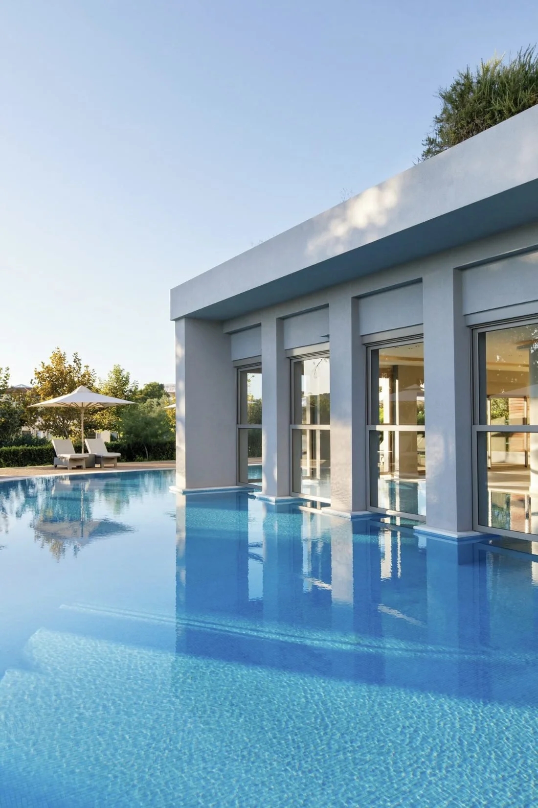 The spa pool at Ikos Olivia, an outdoor pool flowing under the glass-fronted spa building