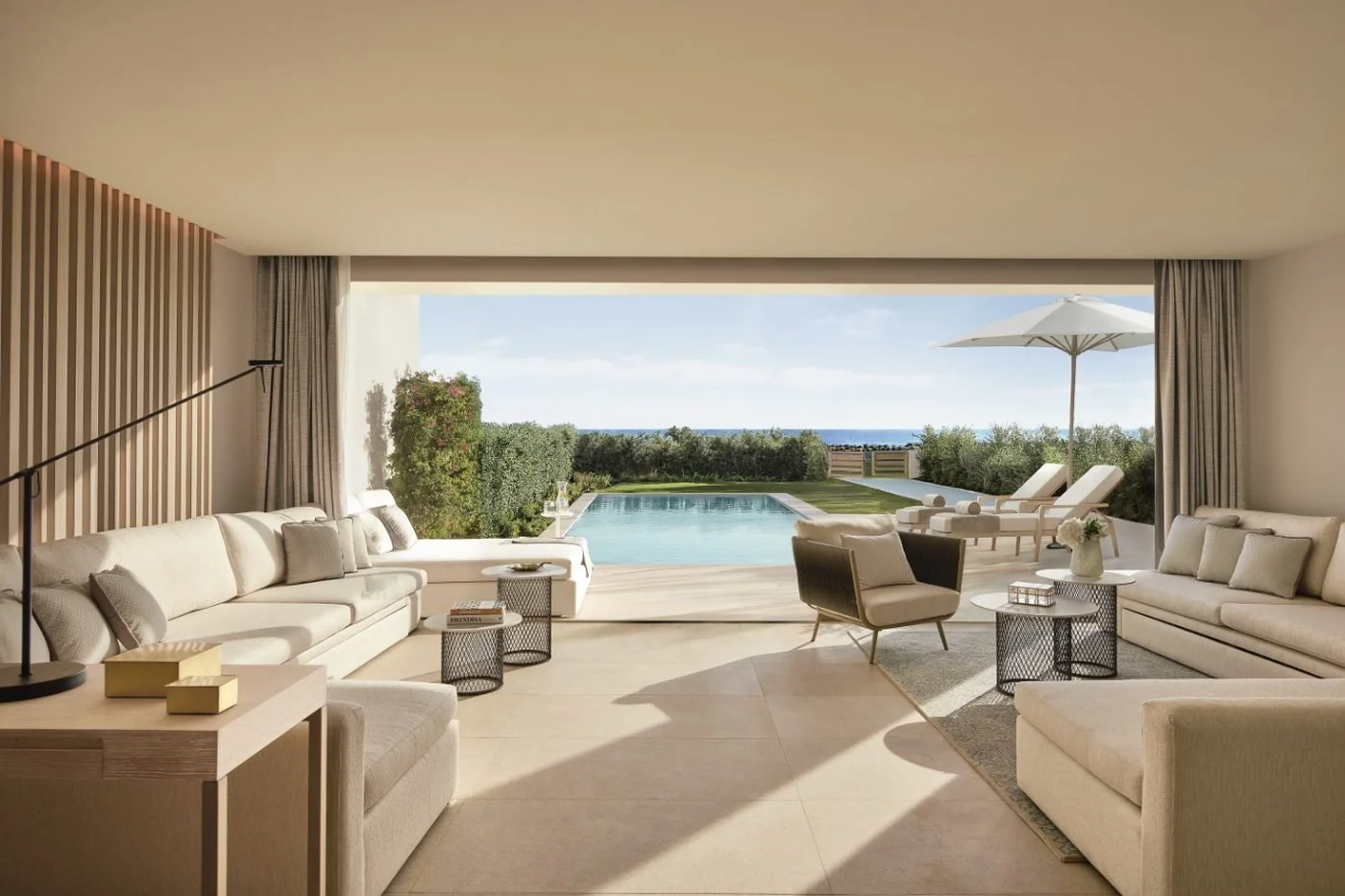 The living room of a Deluxe Two Bedroom Suite Private Pool Sea View opening onto a long private pool and loungers