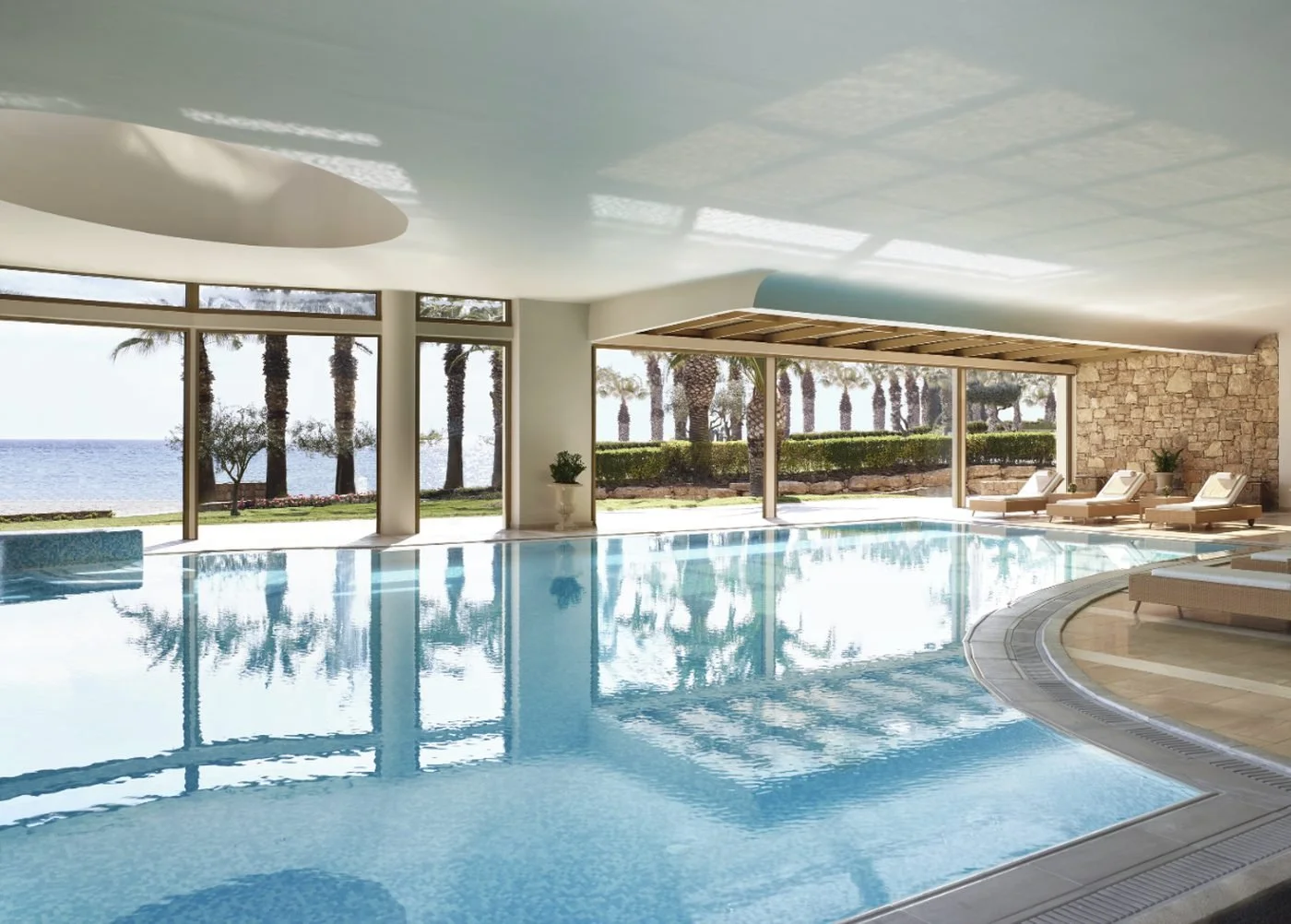 The heated indoor pool at My Spa, with tall windows onto palm trees and the sea