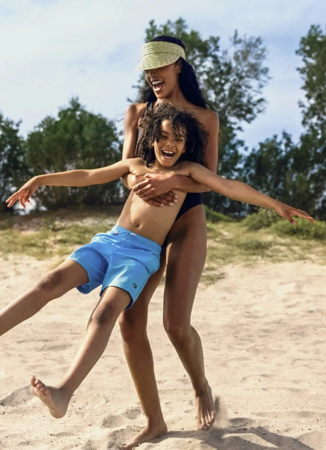 A laughing mother swinging her young son round on the beach at Ikos Porto Petro