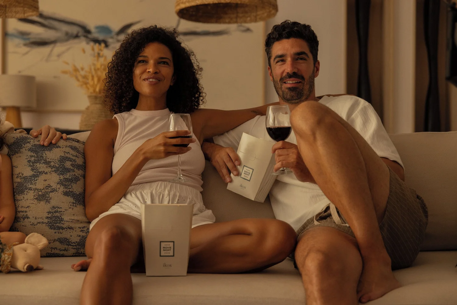 A couple relaxing with glasses of red wine on a sofa in a villa at Ikos Andalusia