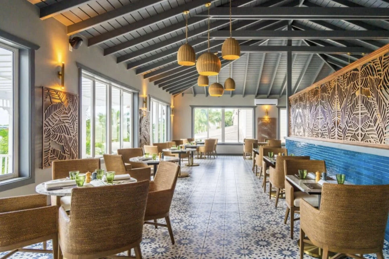 A bright restaurant with patterned tiles and rattan chairs