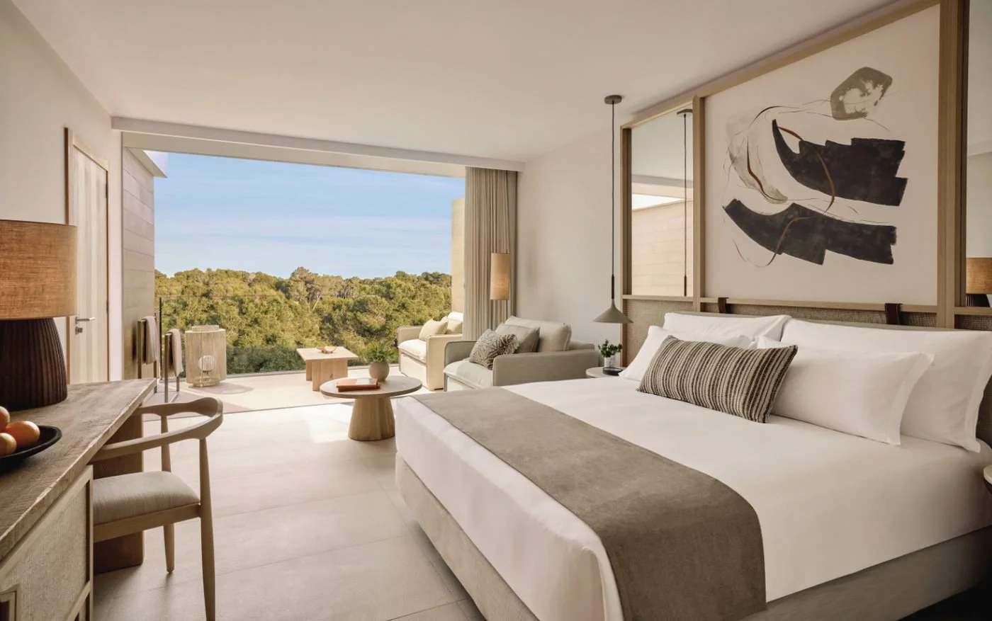 A Family Room with a large bed facing a balcony and pine-covered hills