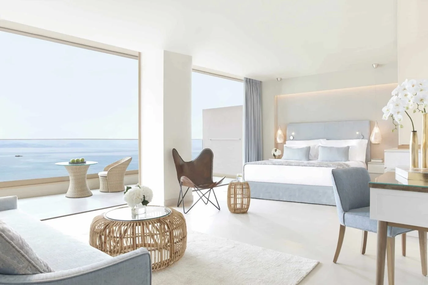 A Panorama Junior Suite with a seating area beside floor-to-ceiling windows facing the sea