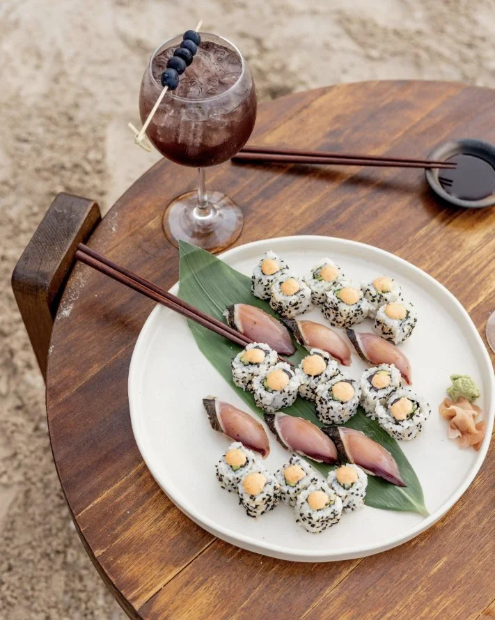 Sushi and a cocktail on a beach table