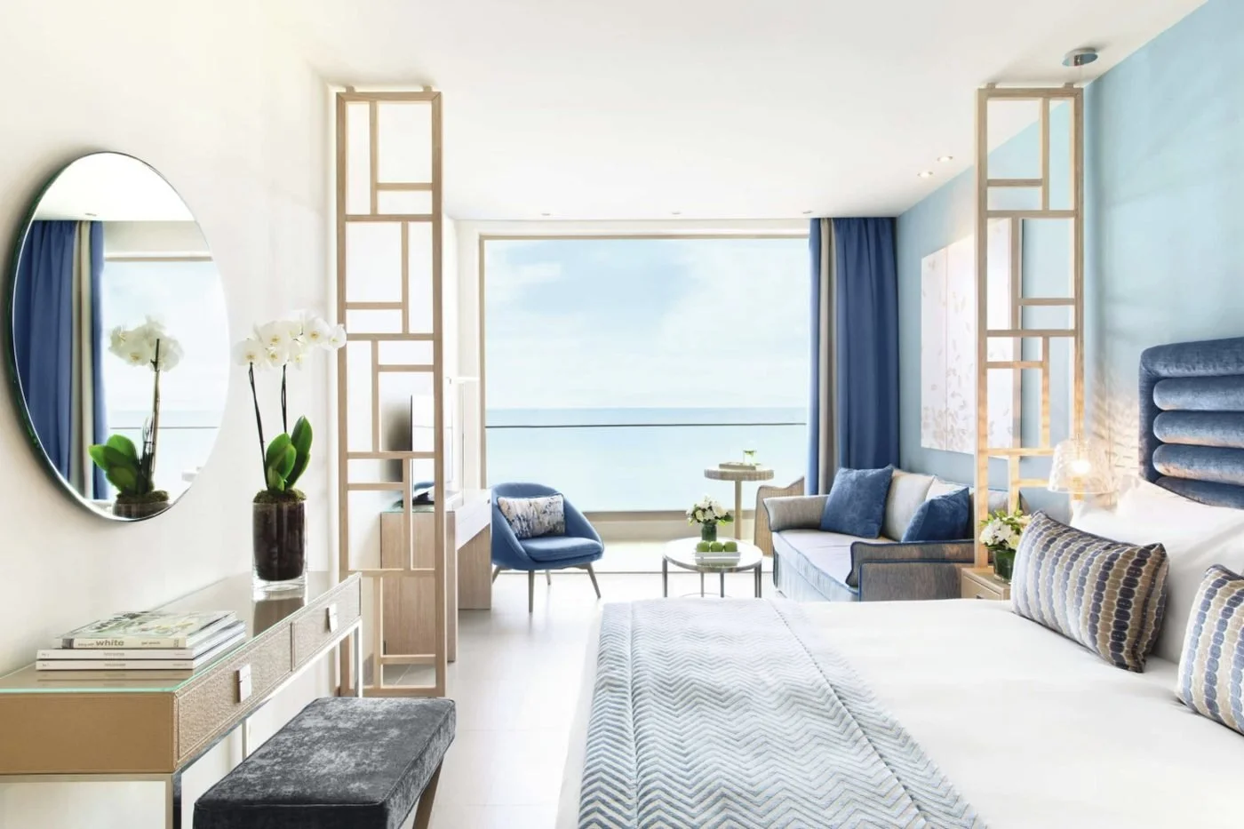 A Deluxe Junior Suite at Ikos Oceania with a king bed, a sitting area and a balcony looking out to sea