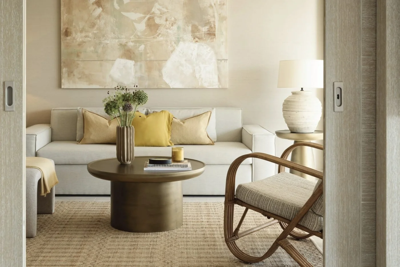 The living room of a One Bedroom Bungalow Suite, with a cream sofa, round wooden table and rattan armchair