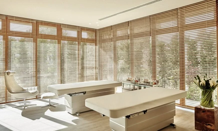 A sunlit double treatment room at the Spa Retreat, Sani Asterias, with wooden blinds and white lilies