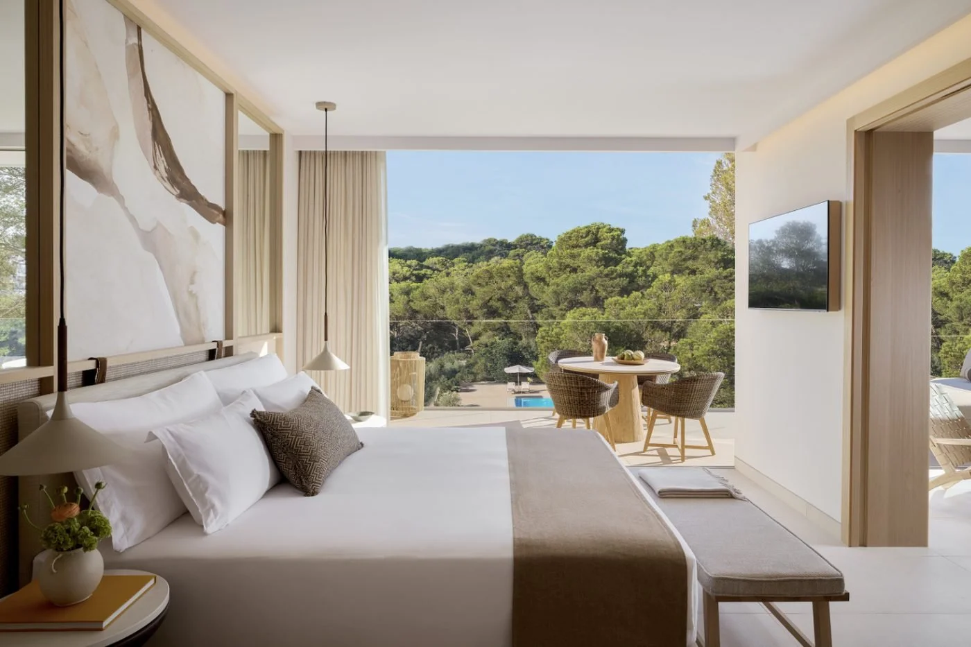 A One Bedroom Suite bedroom opening onto a balcony with a dining table and a pool below