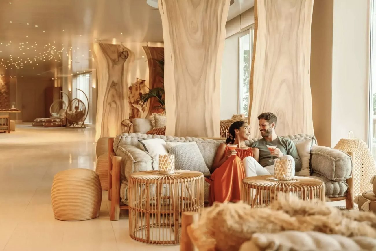 A couple sharing cocktails on a sofa in the Deluxe lounge